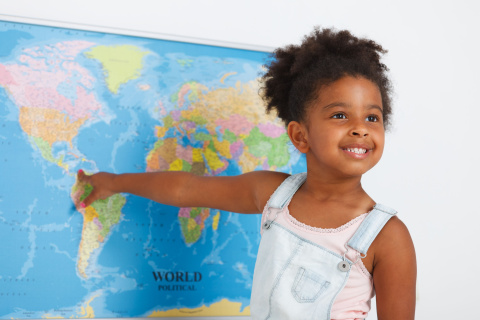 Child pointing at a map and smiling